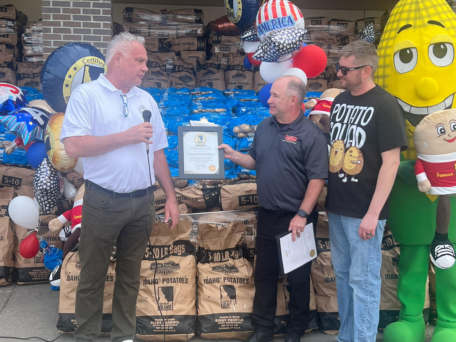Patrick Mills of the Idaho Potato Commission presents County Fair owners Justin Luther and Steve Clarke a certificate of appreciation from the IPC.