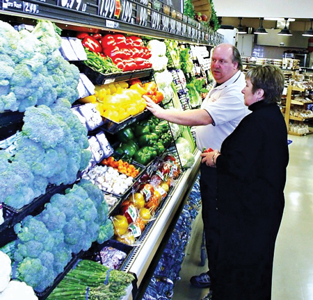 A produce manager recomending items to a customer. 