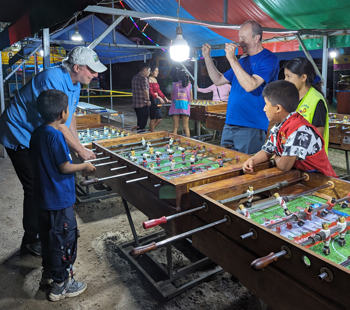 Neil Millman and Jim Provost of I Love Produce play foosball with some local children at a carnival in Pichanaqui, Peru.